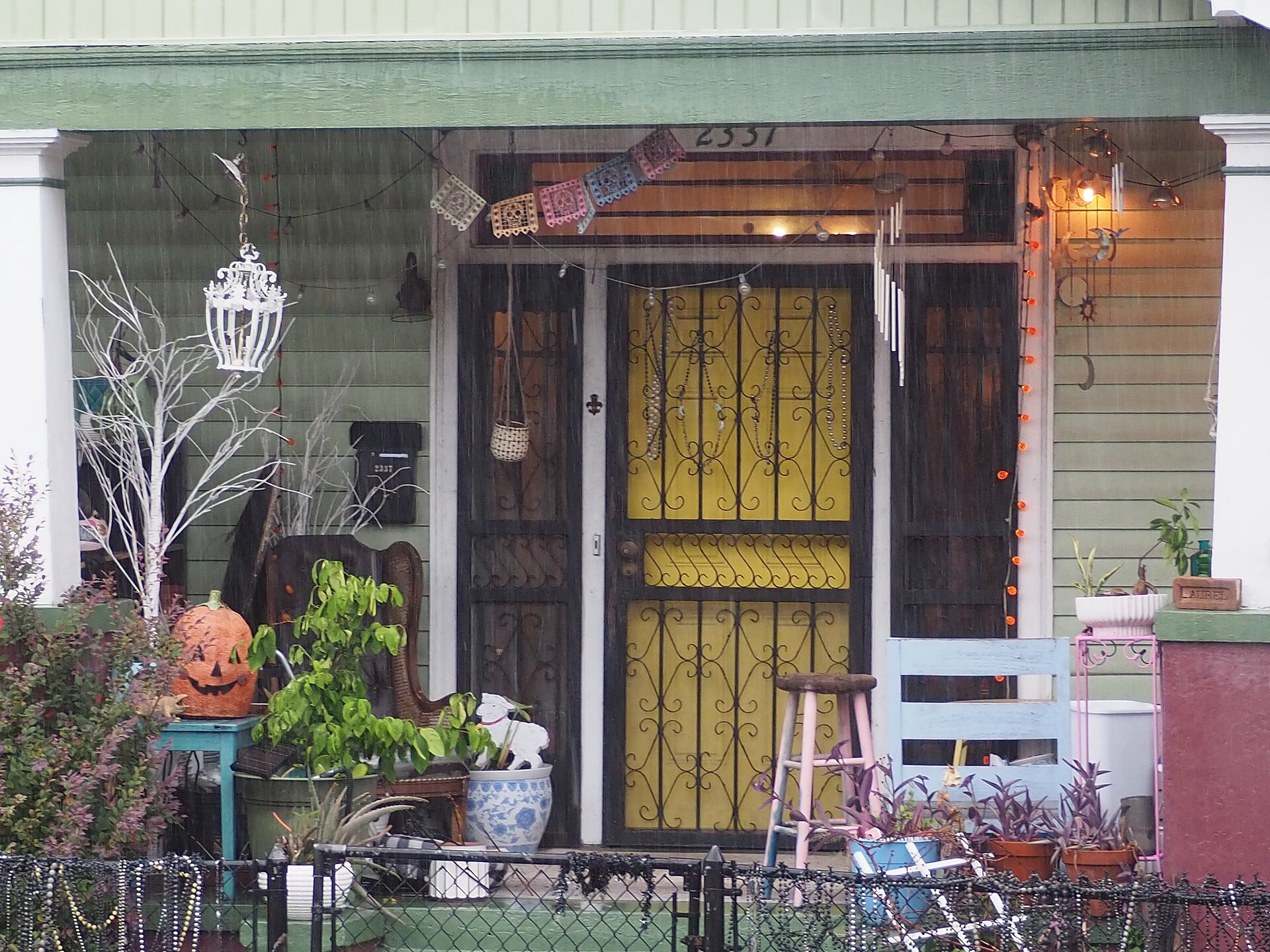 Hiên nhà trang trí Halloween với bí ngô, dây đèn cam và cờ giấy đầu lâu nhiều màu ở New Orleans