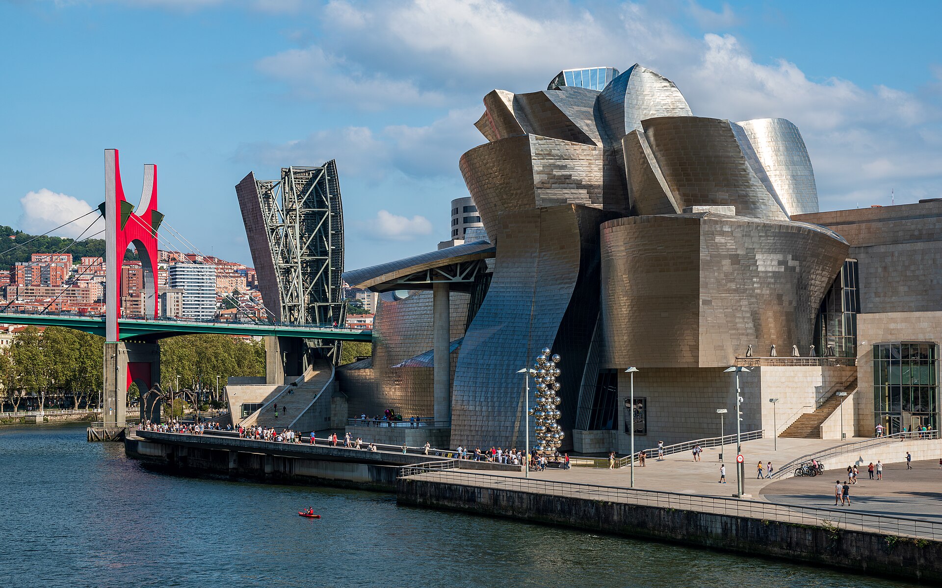 Bảo tàng Guggenheim Bilbao vỏ titan uốn cong bên sông Nervion với cầu La Salve đỏ