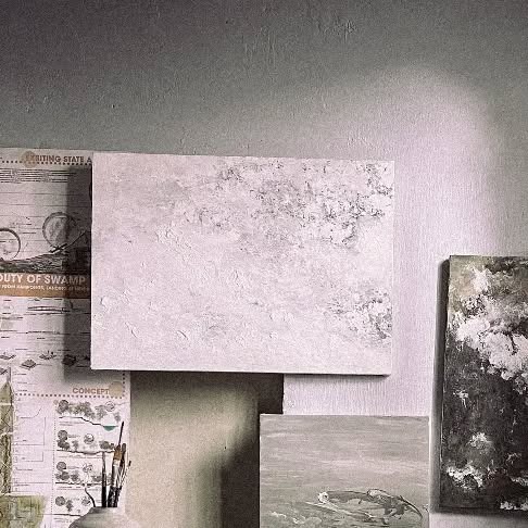 Ba tấm tranh khổ khác nhau dựa vào tường và bệ, bề mặt nhiều lớp chất liệu trắng xám