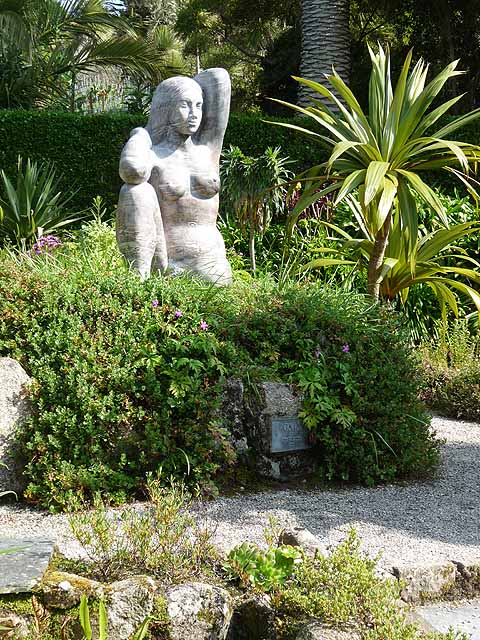 Tượng Gaia bằng đá giữa bồn cây xanh và cọ trong vườn Tresco Abbey