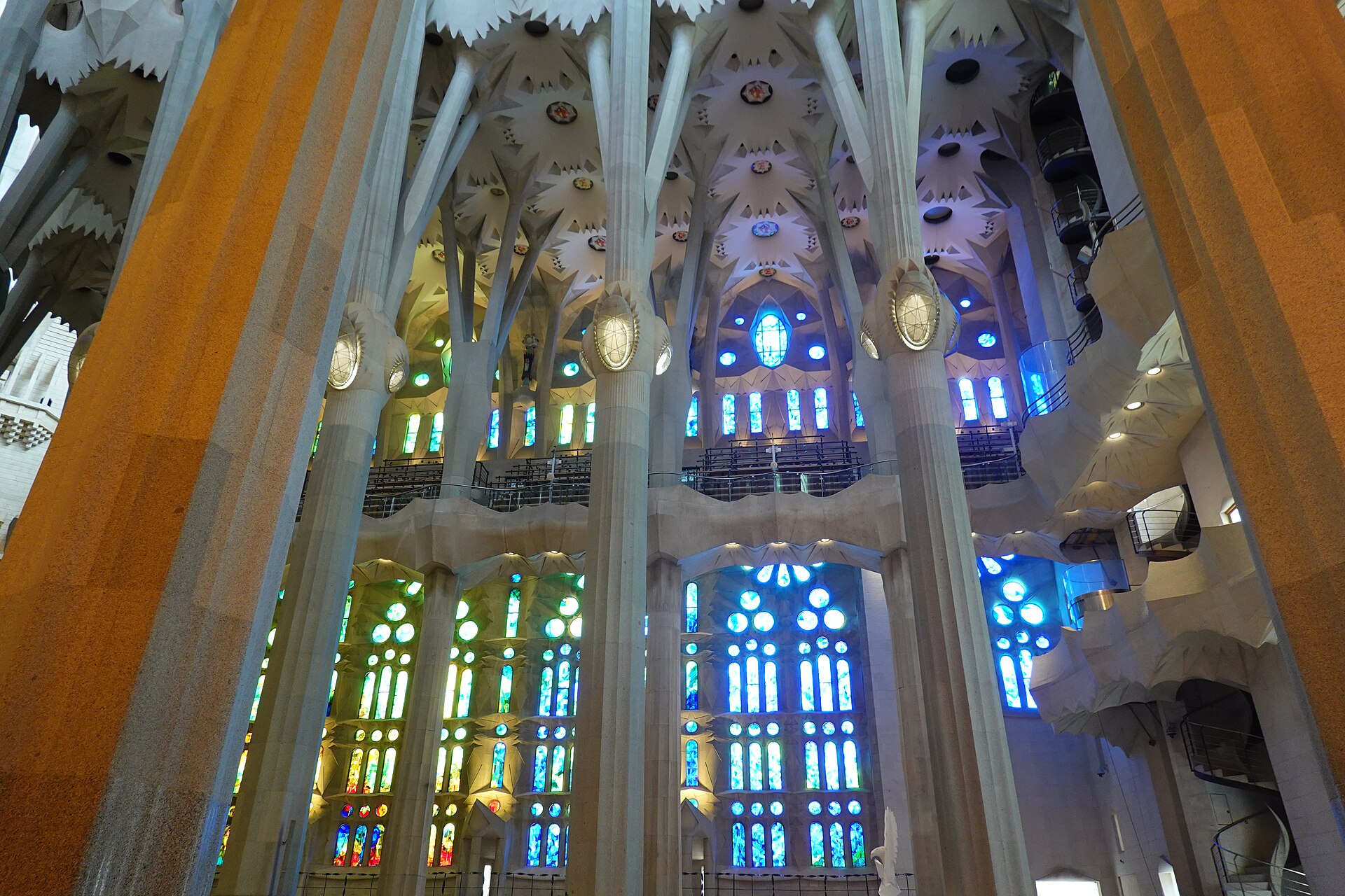Kính màu xanh dương và xanh lá phía Bắc gian giữa Sagrada Família chiếu sáng các hàng cột đá