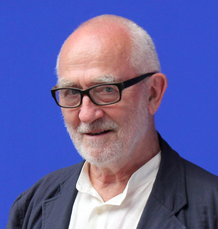 Chân dung Peter Zumthor đeo kính đen cười trên nền xanh