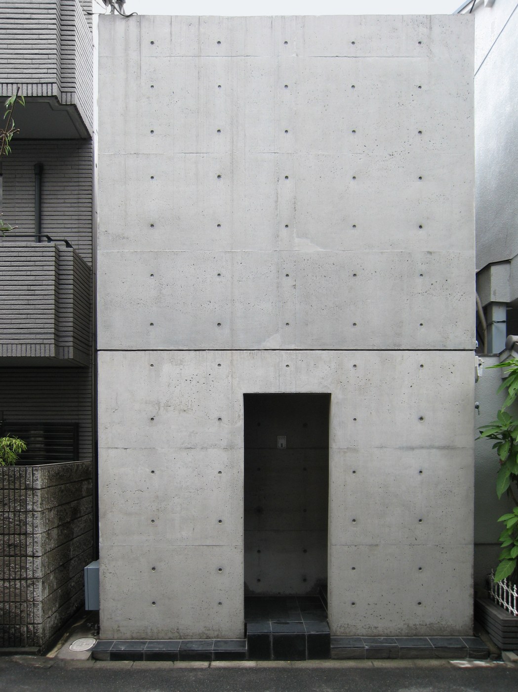 Mặt tiền bê tông hẹp của Row House Sumiyoshi chen giữa hai nhà phố