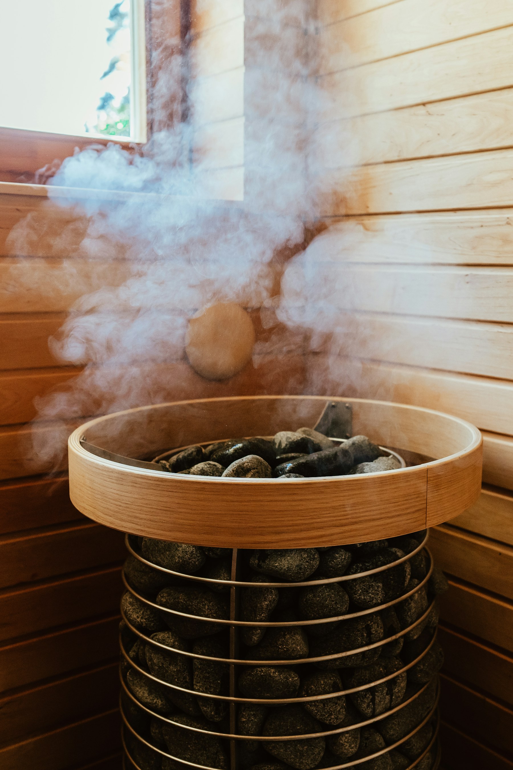 Hơi nước bốc lên từ đống đá trên một lò xông hơi tròn bằng gỗ