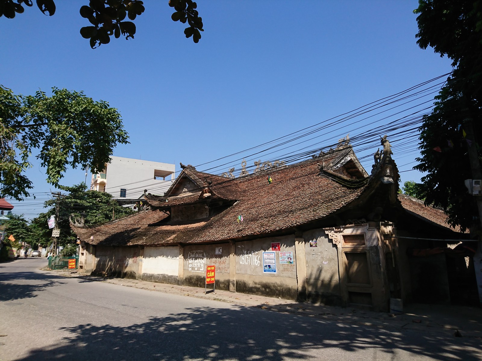 Một ngôi đình mái ngói cong nằm ngay bên đường làng, tường hồi xây gạch trần, trước sân là khoảng đất trống