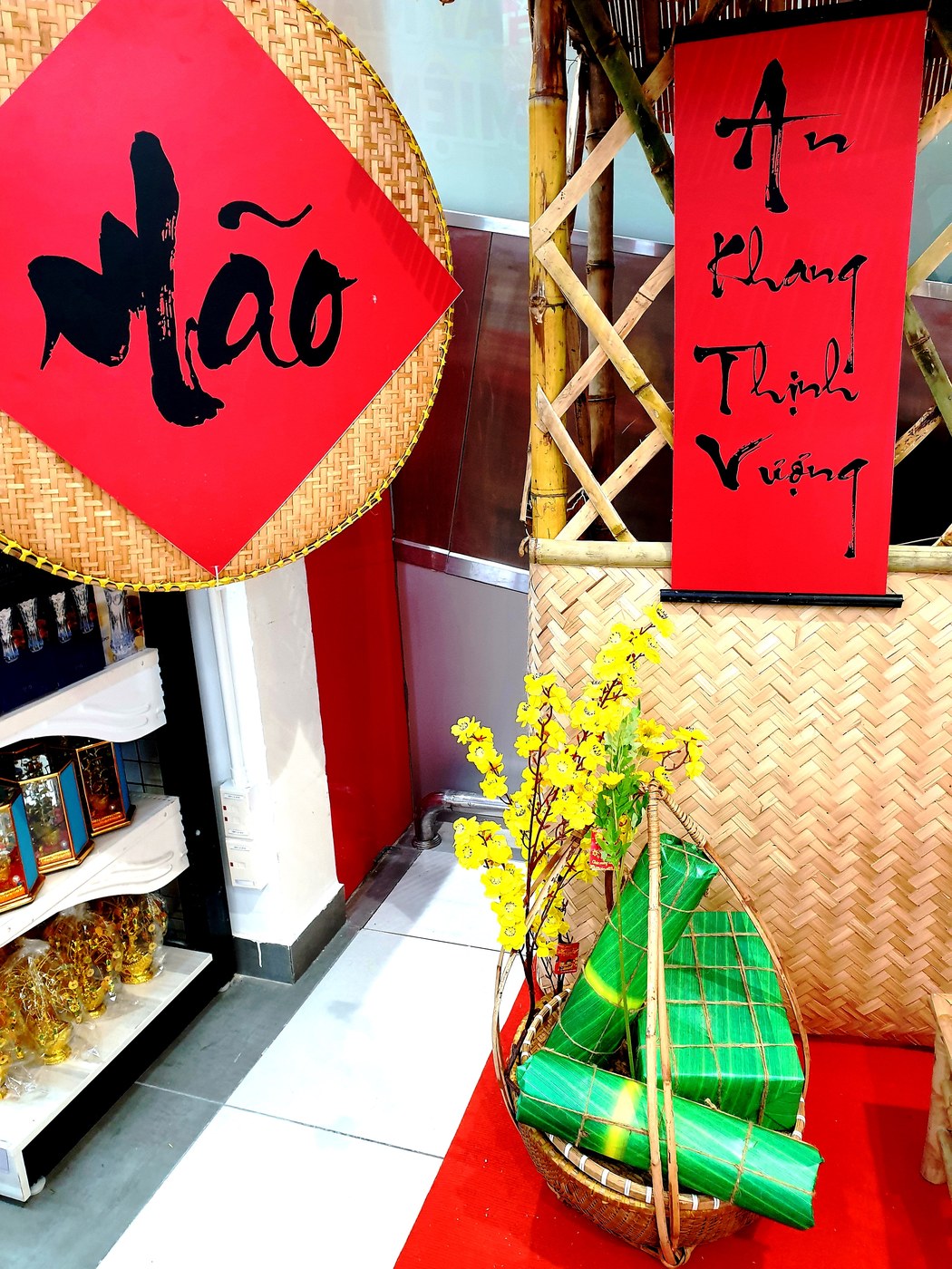 Mâm bày bánh chưng, bánh tét và dưa hấu bổ đôi ruột đỏ đặt cạnh câu đối đỏ