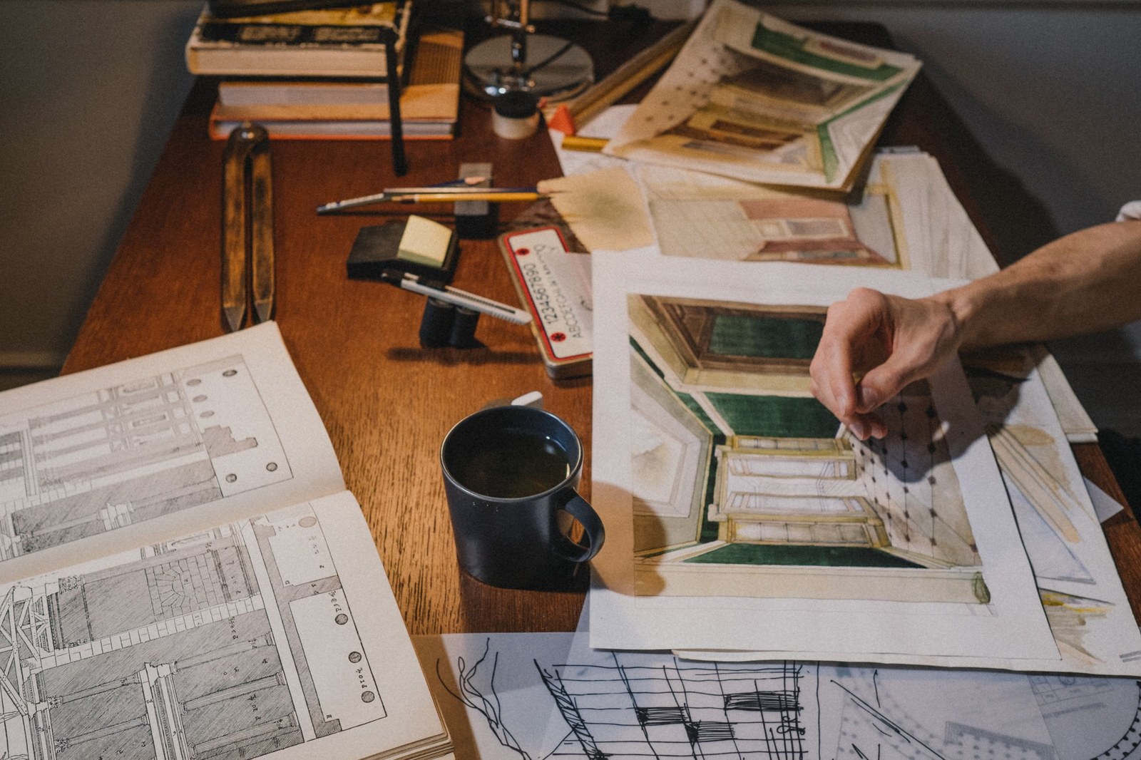 Một tập portfolio in giấy đang được lật qua nhanh trên bàn, chỉ dừng lại ở vài trang có ảnh render lớn