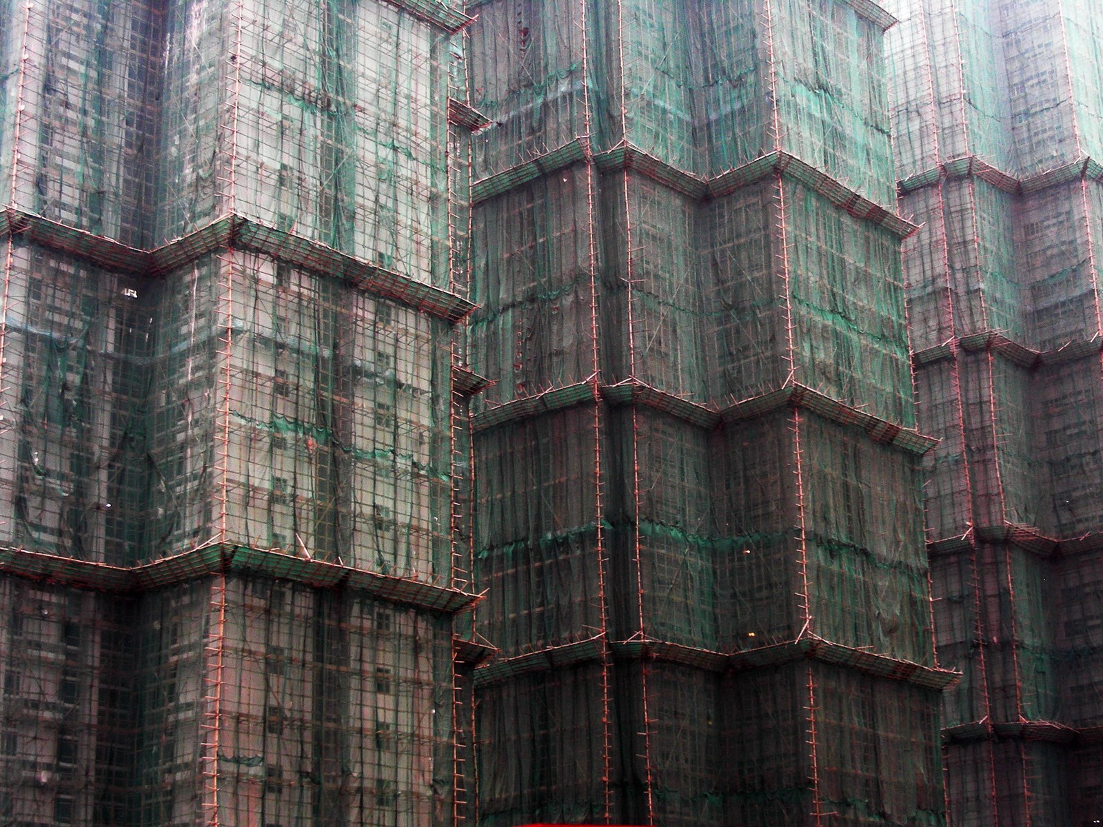 Low-E — Giàn giáo tre bọc lưới bao quanh một toà