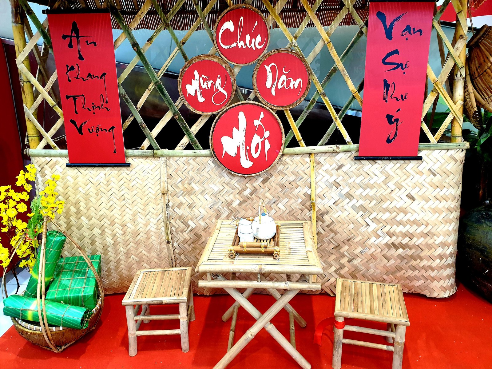Liễn đỏ viết thư pháp treo trên phên tre, bàn ghế tre phía trước