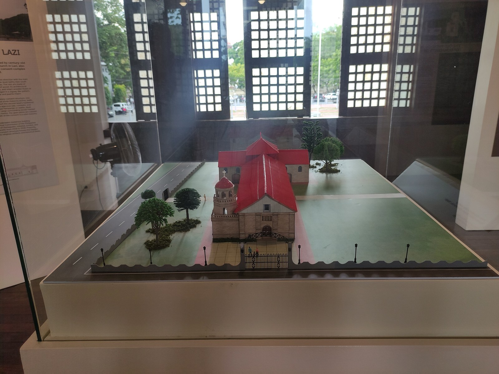 Mô hình nhà thờ mái đỏ giữa sân cỏ trong tủ kính