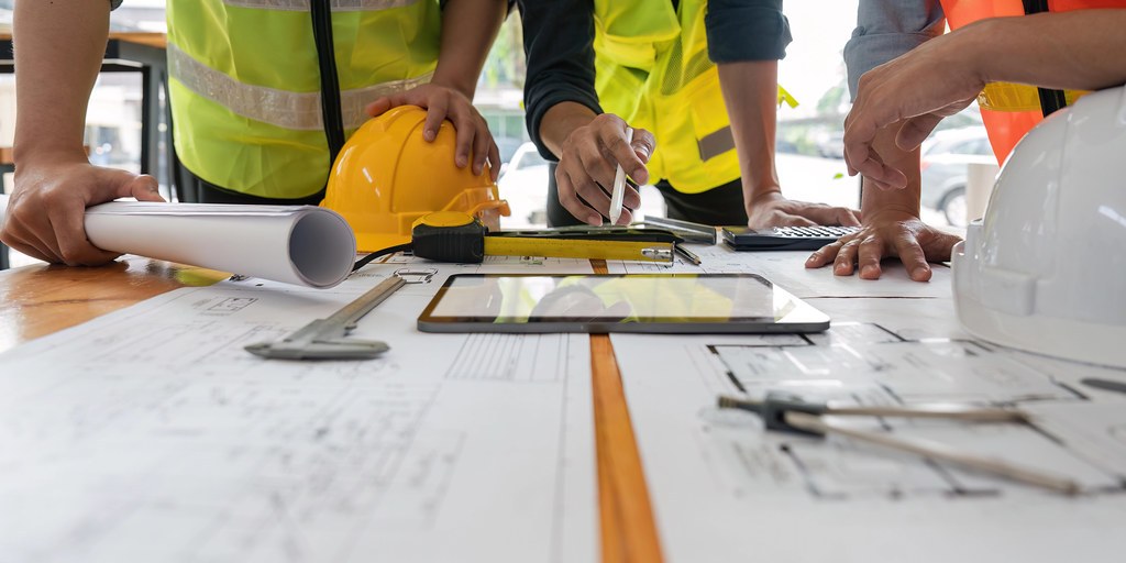 Hai người đội mũ bảo hộ cùng xem màn hình một máy tính bảng ngoài công trường