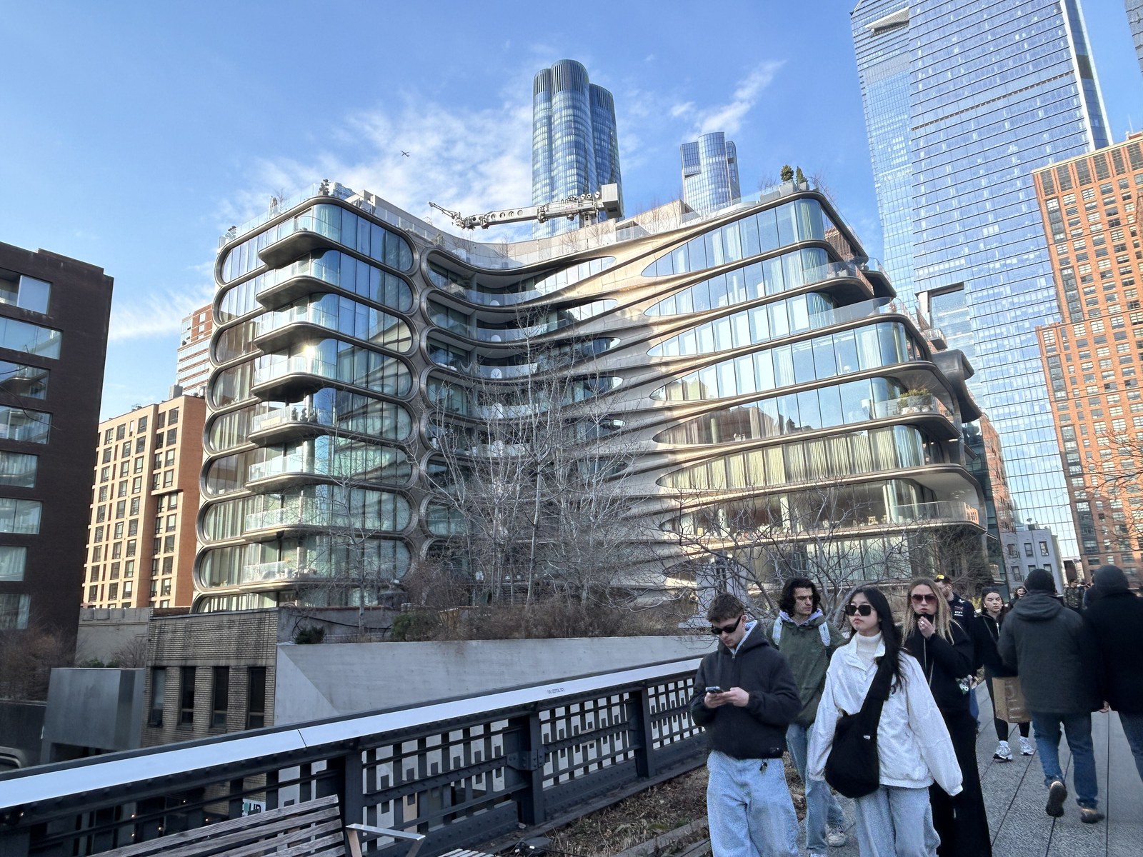 High Line — Khách đi bộ trên High Line cạnh tòa căn hộ cao cấp 520 West 28th của Zaha Hadid, tháp Hudson Yards phía sau
