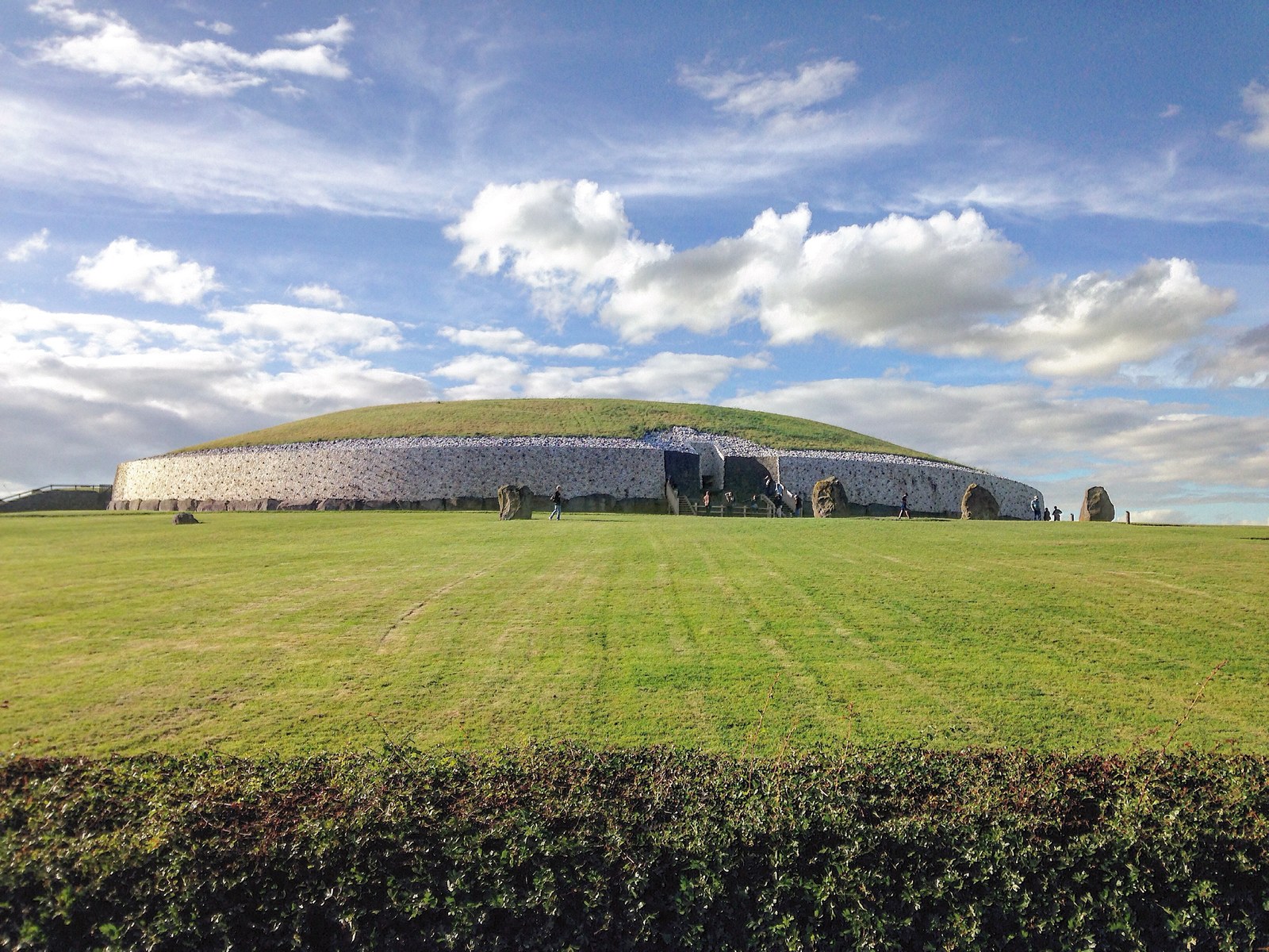 Gò mộ đá New Grange ở Ireland nhìn từ phía trước, tường đá trắng ốp mặt tiền, mái cỏ hình vòm, lối vào trung tâm có các phiến đá đứng phía trước bãi cỏ