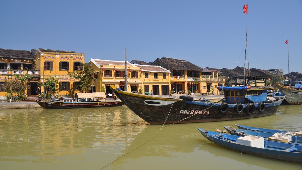 Ghe thuyền gỗ đậu trên sông Hoài trước dãy phố cổ Hội An mái ngói, một chiếc ghe lớn sơn đen mang số hiệu QNa2997