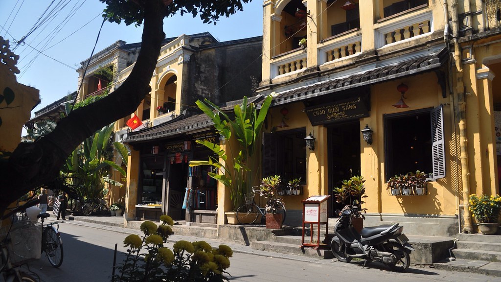 Con đường nhỏ trong phố cổ Hội An về chiều, đèn lồng tròn đỏ trắng và xanh treo ngang qua đường, hai bên là nhà cổ mái ngói
