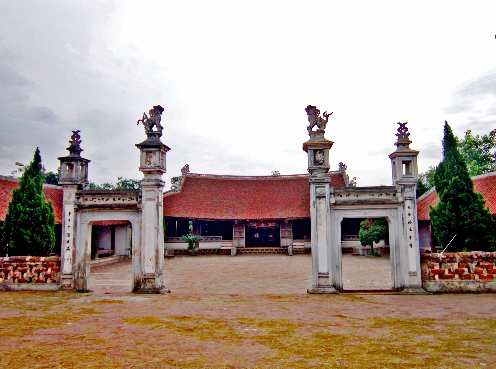 Cổng đình Mông Phụ với hai trụ đá có tượng lân trên đỉnh, cổng sắt mở ra sân gạch, phía sau là nhà chính mái ngói đỏ cong