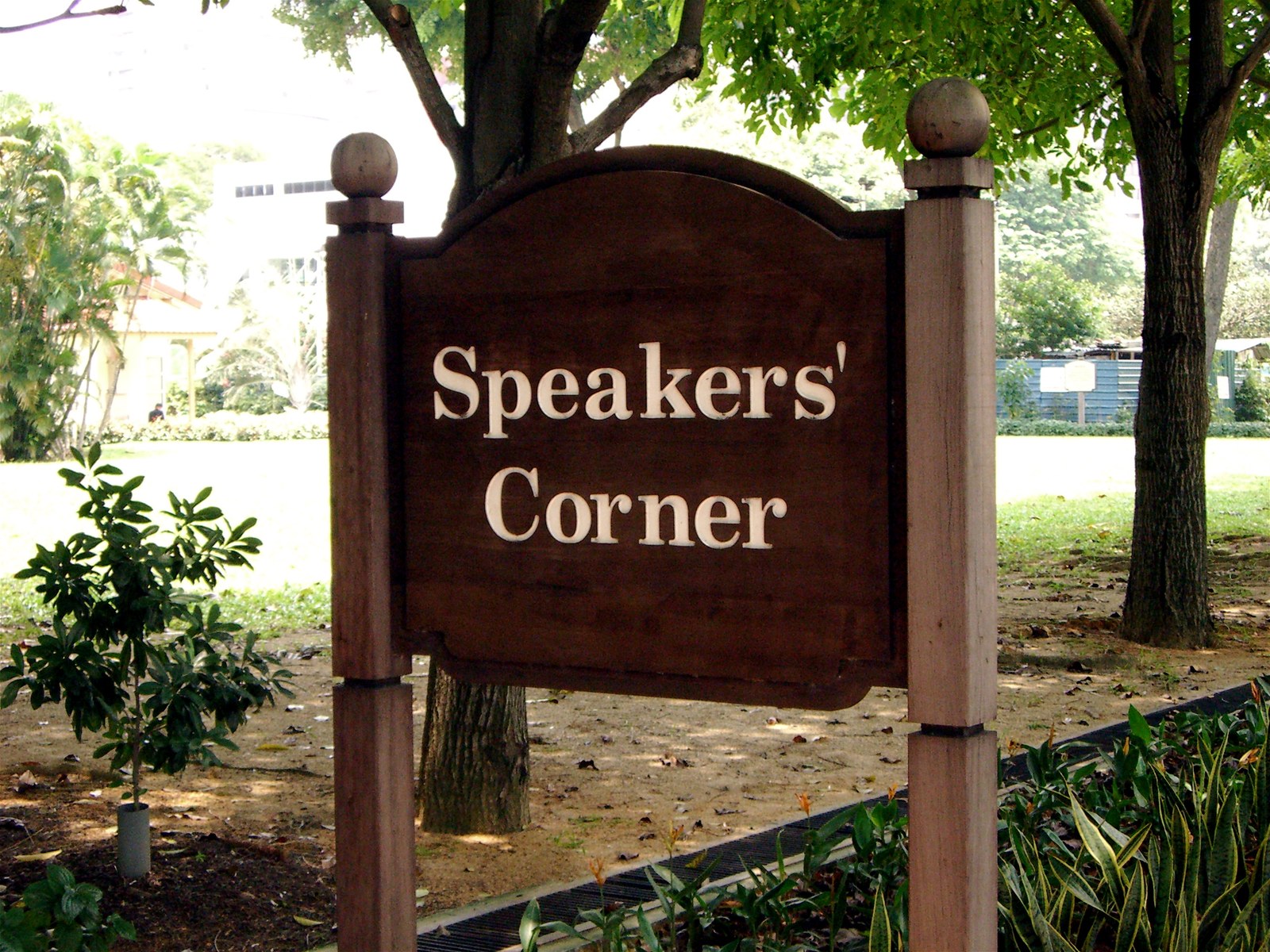 Biển gỗ khắc chữ Speakers' Corner đặt giữa bãi cỏ có cây xanh