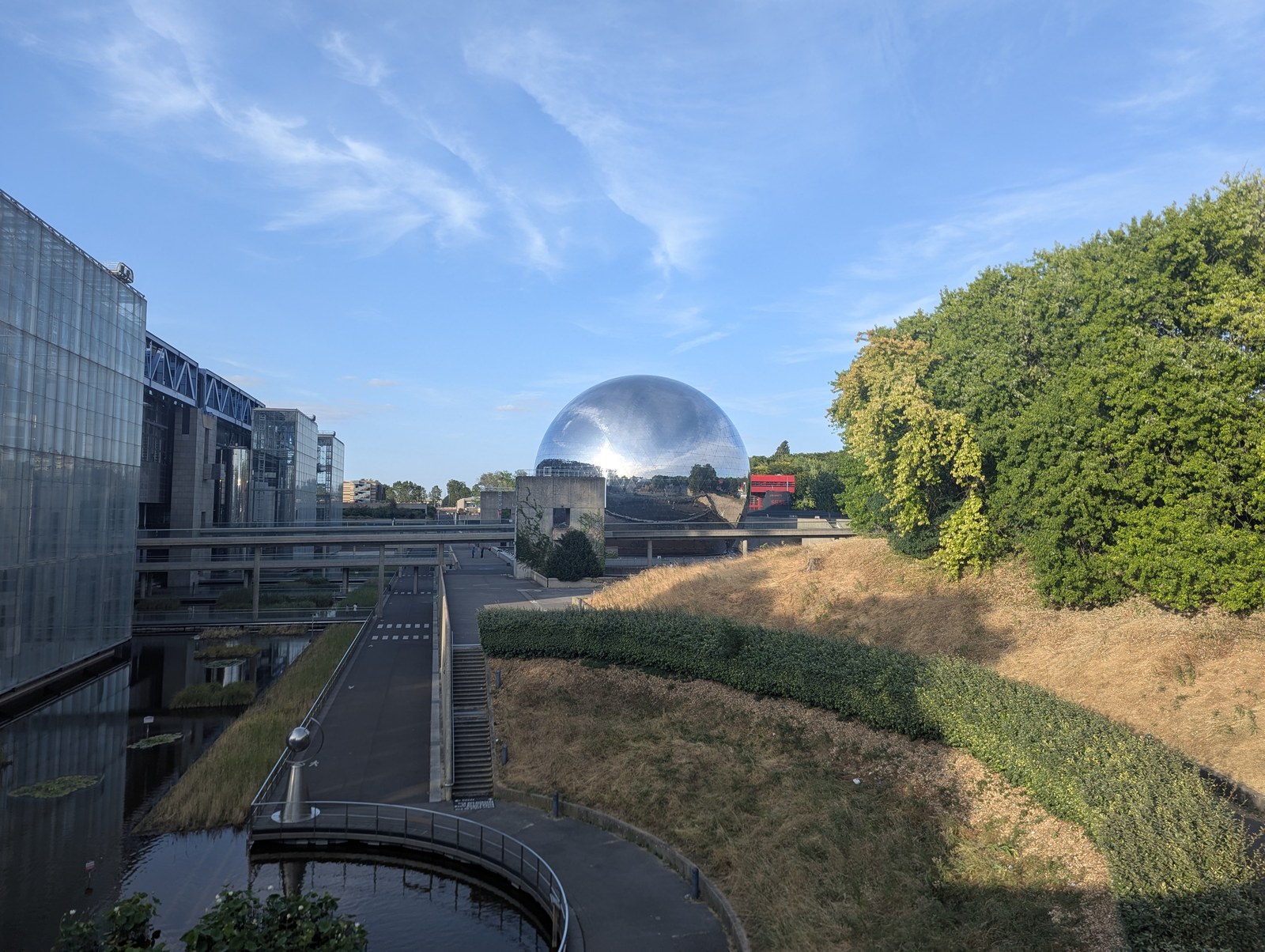 Lối đi bê tông cong ven hồ nhỏ dẫn về phía mái vòm gương La Géode