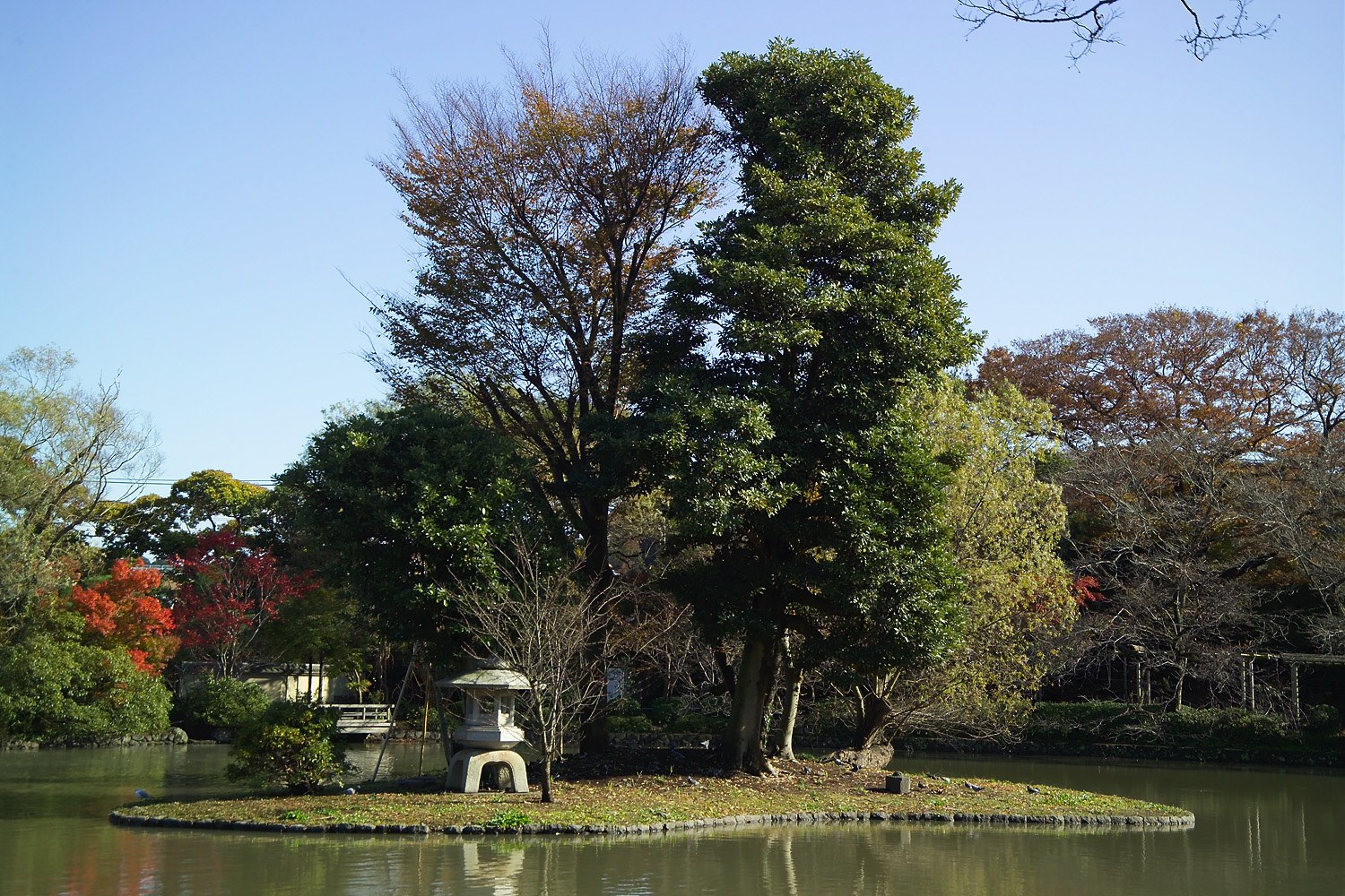 Cây đèn đá đứng trên hòn đảo nhỏ giữa hồ, cây cối bao quanh