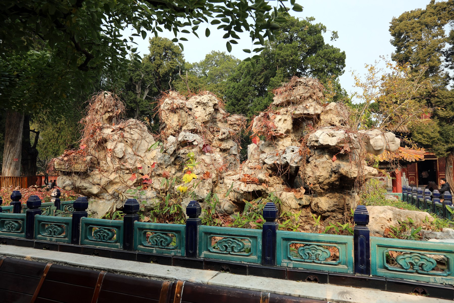 Nhiều khối đá vôi lớn đầy lỗ thủng chồng lên nhau thành một dãy núi nhân tạo, lan can sơn xanh phía trước